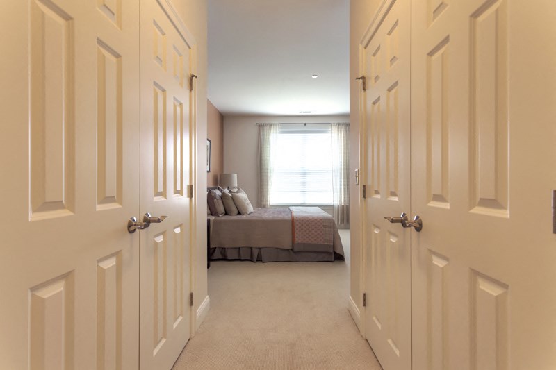 a bedroom with white doors and a bed and a window