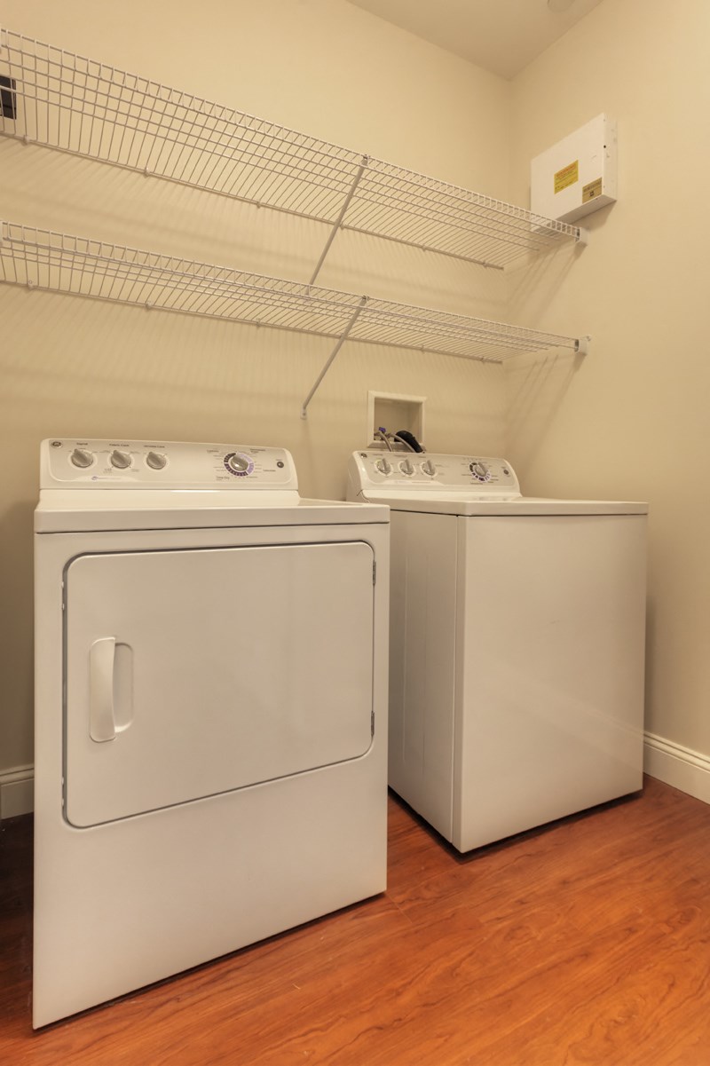 two washes and dryers in a room with wood flooring and a shelf