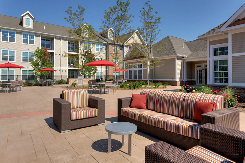 a patio with furniture and umbrellas in front of apartments