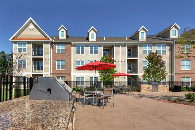 a patio with tables and umbrellas in front of an apartment building