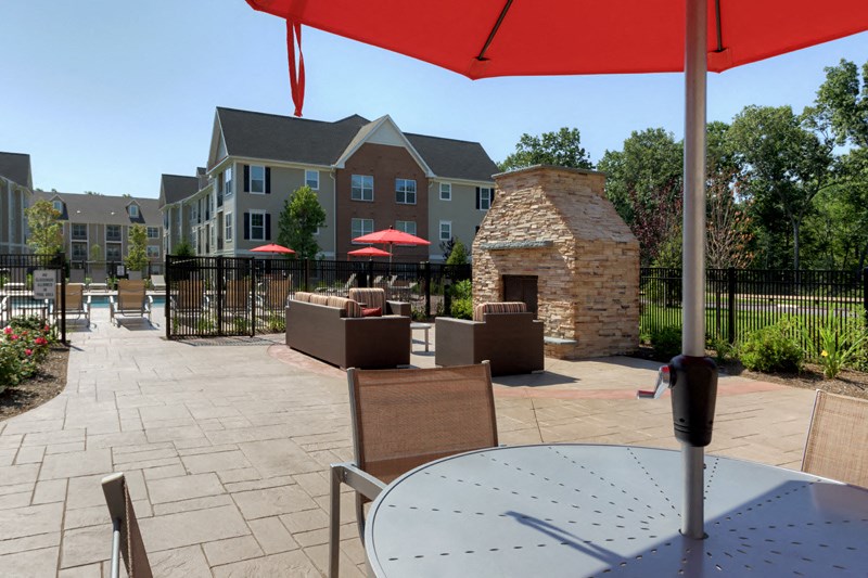 a patio with a table and chairs and a brick fireplace
