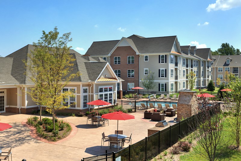 a courtyard with tables and umbrellas in front of an apartment building