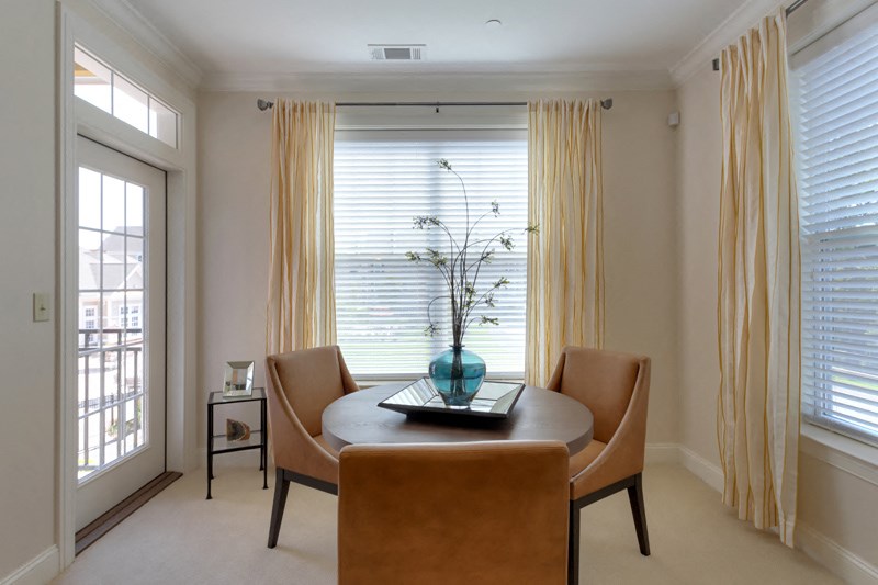 a dining room with a table and chairs in front of a window