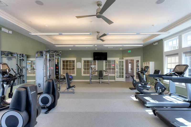 a gym with cardio equipment and a ceiling fan