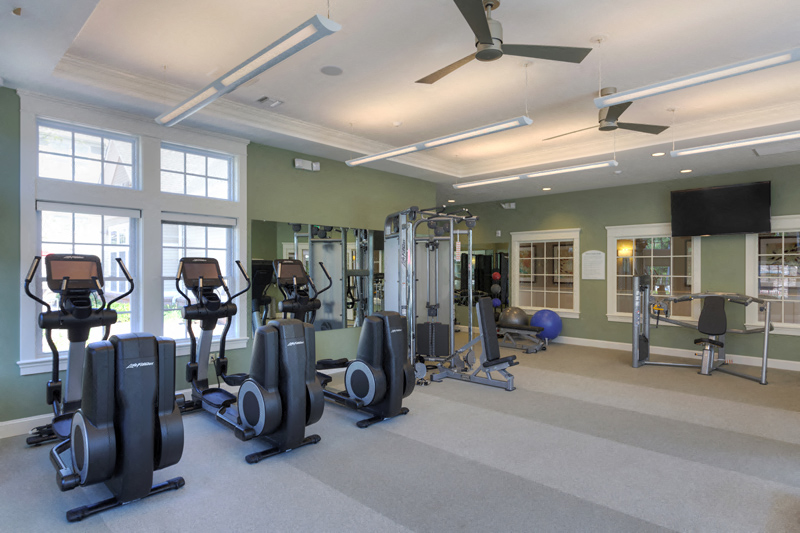 a gym with weights and cardio equipment in a large room with windows