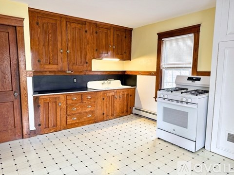A kitchen with white tiled floors and wooden cabinets.