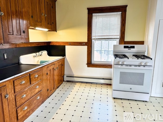 A kitchen with a white tiled floor and wooden cabinets.