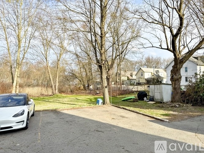A white car is parked on a driveway in front of a house.
