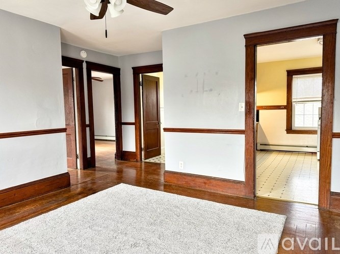 A room with a white rug and a ceiling fan.