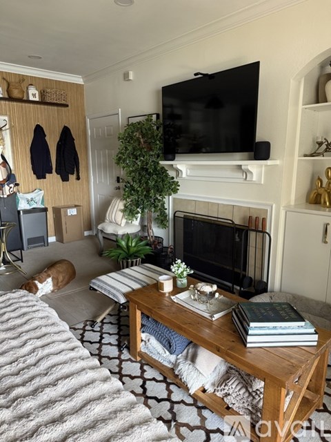 A living room with a fireplace and a television mounted above it.