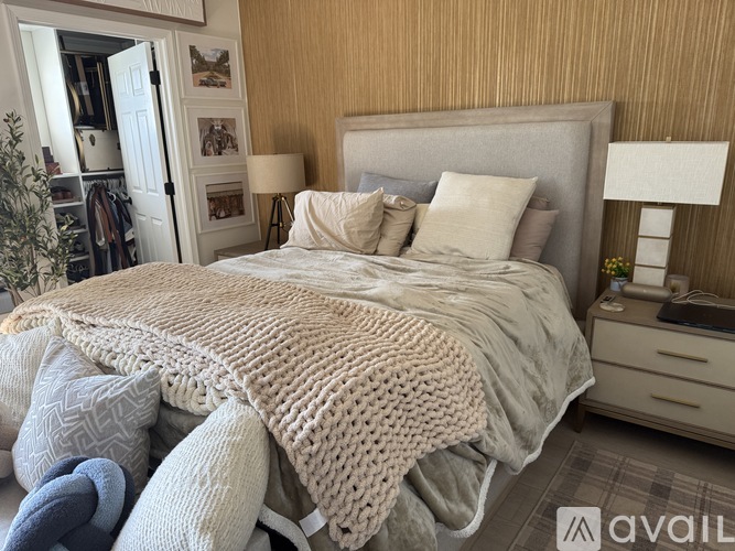 A bed with a beige blanket and pillows in a room.