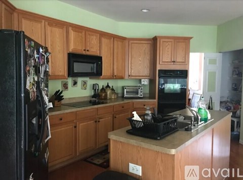 A kitchen with wooden cabinets and a black refrigerator.