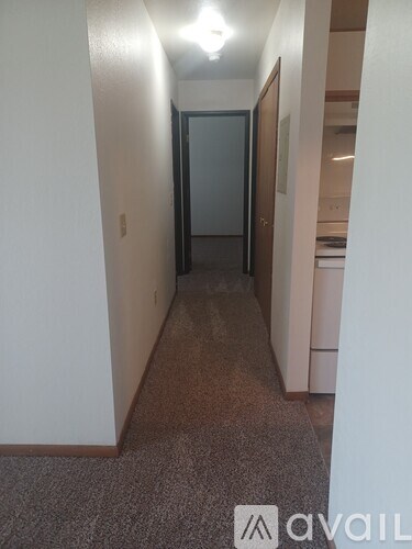 A hallway with a carpeted floor and white walls.