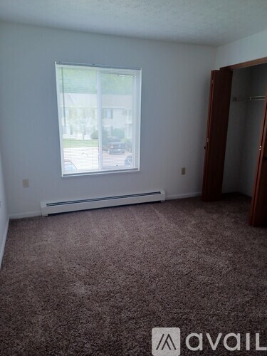 A room with a window and a carpeted floor.