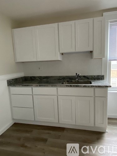 A kitchen with white cabinets and a marble countertop.