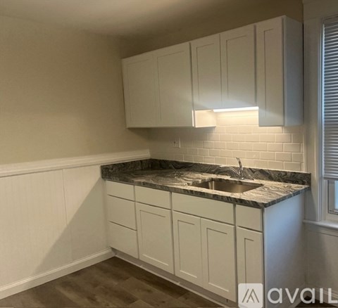 A kitchen with white cabinets and a marble countertop.