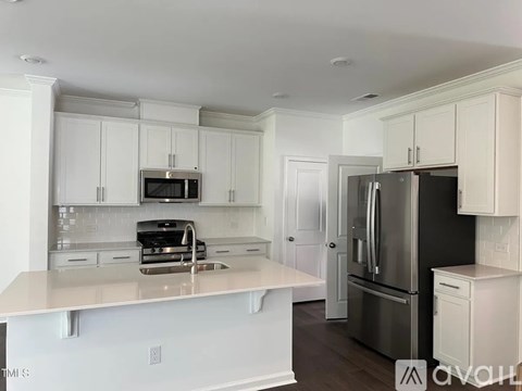 A kitchen with white cabinets and a black refrigerator.