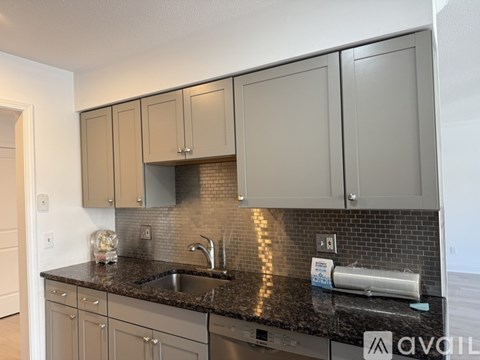 A kitchen with grey cabinets and a black countertop.
