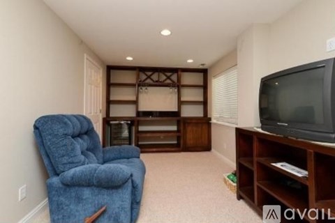 A blue recliner chair is in a living room with a television and a wooden entertainment center.