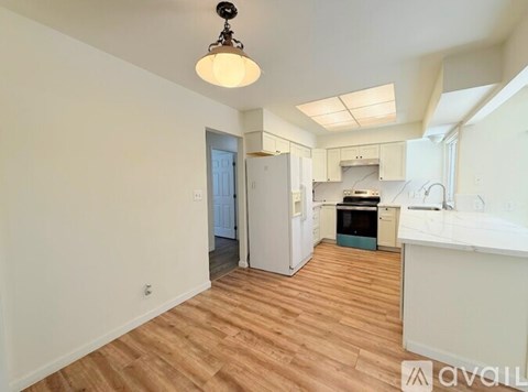 A kitchen with a white counter top and wooden floors.
