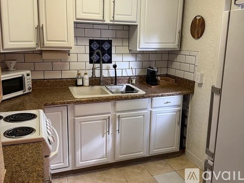 A kitchen with white cabinets and a granite countertop.