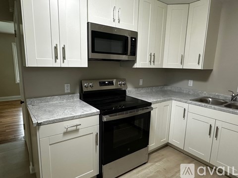 A kitchen with white cabinets and a black stove top oven.