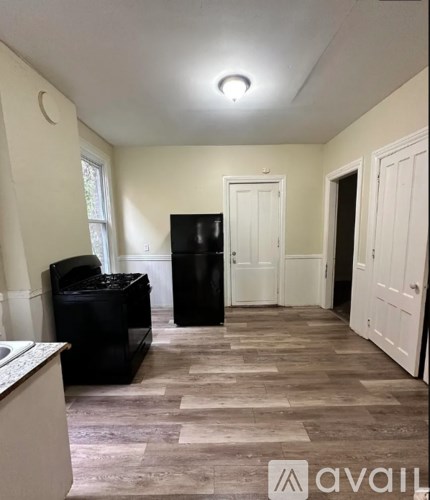 A kitchen with a black fridge and a black trash bin.
