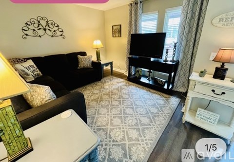 A living room with a black couch and a television.