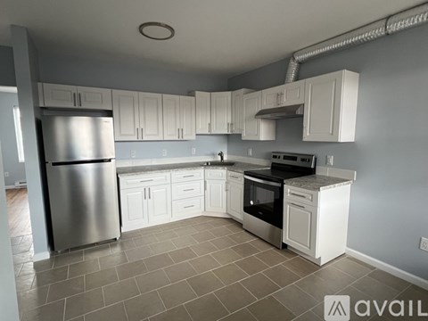 A kitchen with white cabinets and a stainless steel refrigerator.