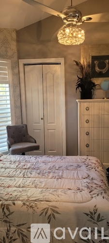 A bedroom with a bed, a dresser, and a ceiling fan.