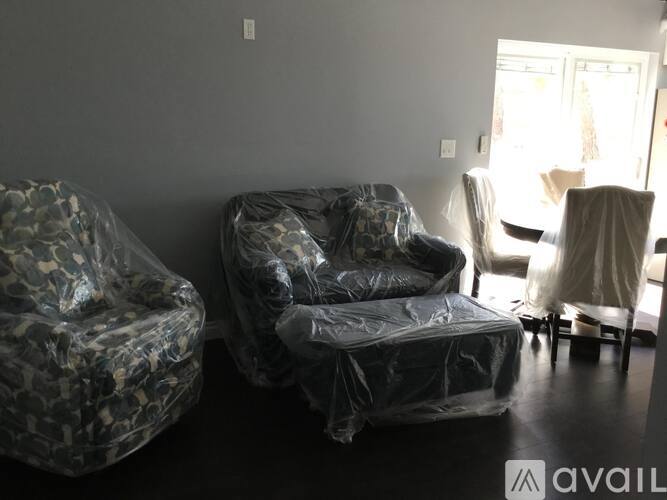 A living room with two chairs covered in plastic.