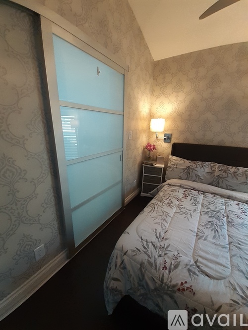 A bedroom with a bed, a nightstand with a lamp, and a window with a view.