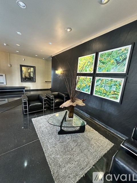 A black and white living room with a grey rug and a vase on a table.