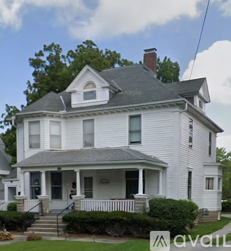 A white house with a grey roof and a porch.