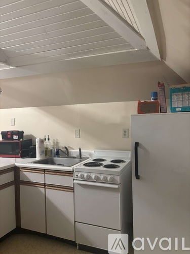 A small kitchen with a white stove and white cabinets.