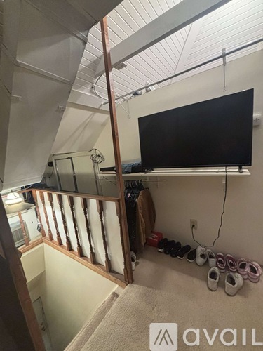 A room with a television, a staircase, and baby shoes on the wall.