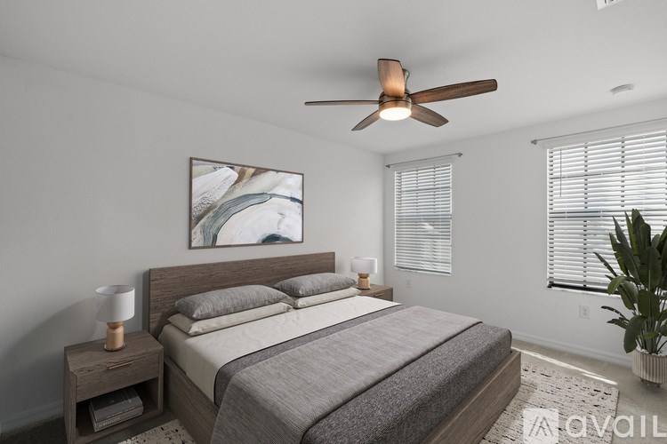 A bedroom with a bed, a ceiling fan, and a painting on the wall.