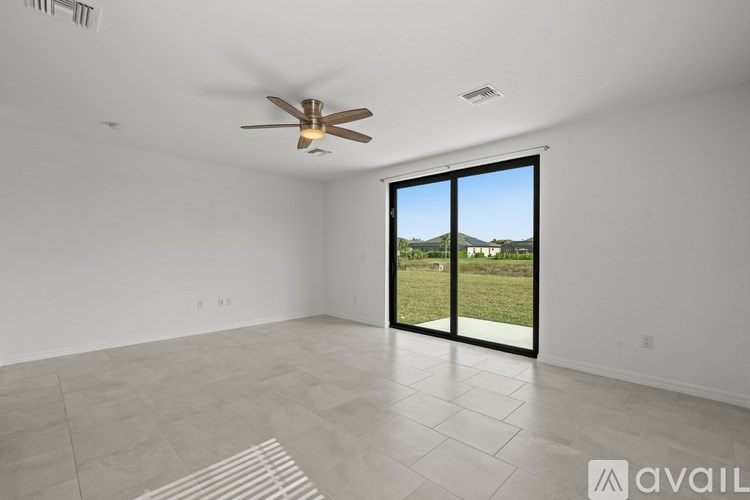 A room with a ceiling fan and sliding glass doors leading to a grassy area.