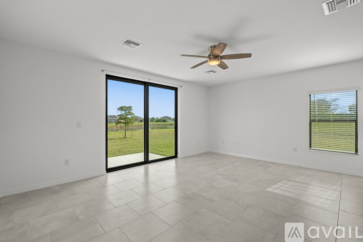 A spacious room with a ceiling fan and sliding glass doors leading to a grassy outdoor area.