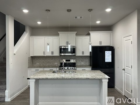 A modern kitchen with a granite countertop and stainless steel appliances.