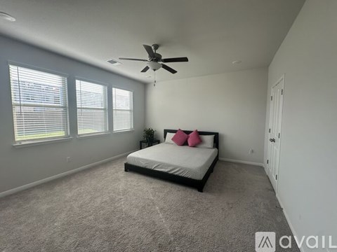 A bedroom with a bed, pillows, and a ceiling fan.