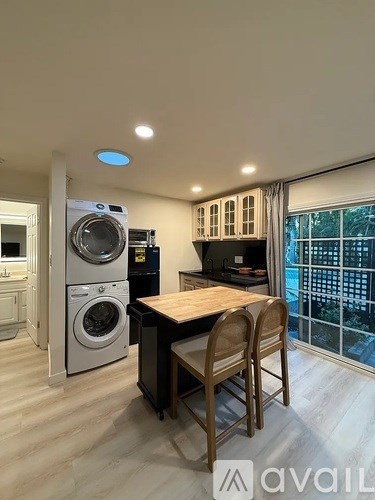 A washing machine is in a kitchen next to a dining table.