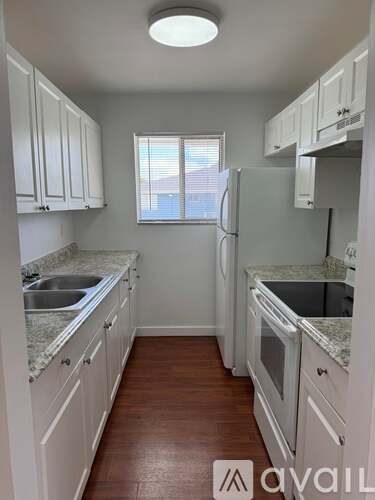 A kitchen with white cabinets and a refrigerator.