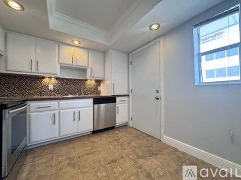 A kitchen with white cabinets and a brown countertop.