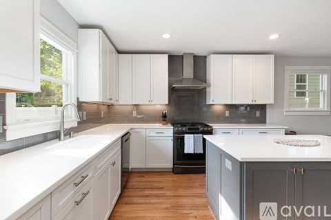 A kitchen with white cabinets and a wooden floor.