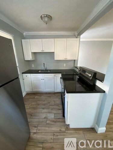 A kitchen with white cabinets and a black countertop.