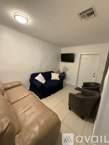 A living room with a brown leather couch and a blue ottoman.