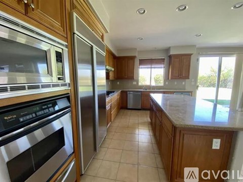 A kitchen with wooden cabinets and stainless steel appliances is available for rent.