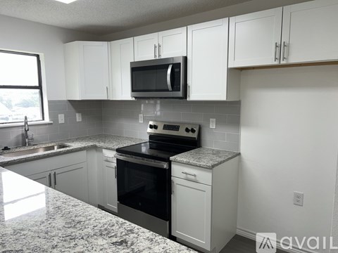 A kitchen with white cabinets and a granite countertop.
