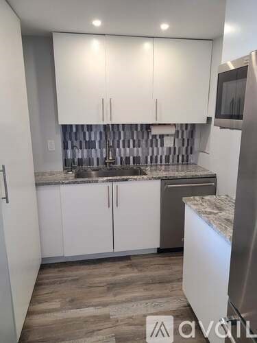 A kitchen with white cabinets and a wooden floor.
